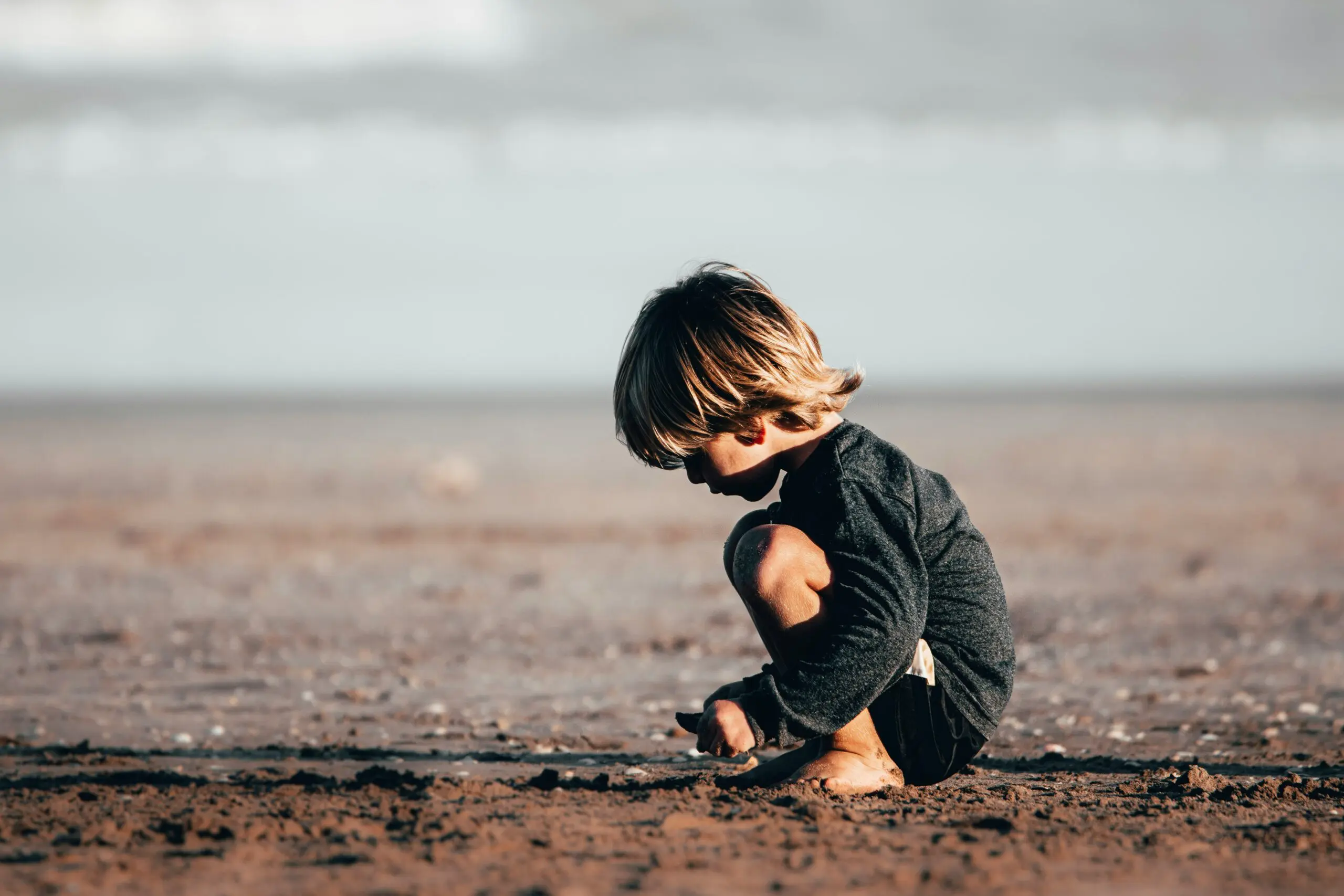 enfant accroupi sur la plage